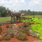 A Horse made of barrels and pipes..adorning top of a pretty flower bed