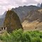 SMALL BUDHIST MONASTERY OVERSHAOWED BY A LARGE ROCK