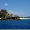 Rock, boat, white sandy beach, and blue waters & sky
